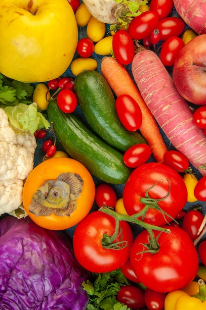 Bovenaanzicht groenten en fruit wortel bloemkool kaki radijs kerstomaten rode kool tomaten op blauwe achtergrond