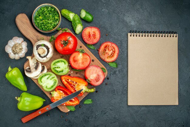 Bovenaanzicht groenten komkommers groene en rode tomaten paprika mes op snijplank