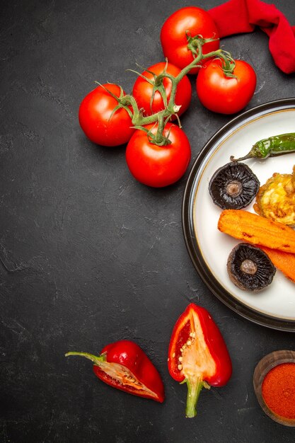 Bovenaanzicht groenten rood tafelkleed tomaten kruiden peper plaat van geroosterde groenten