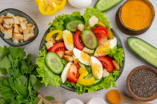 Bovenaanzicht groentesalade met eieren greens en kruiderijen op witte achtergrond maaltijd eten rijpe kleur