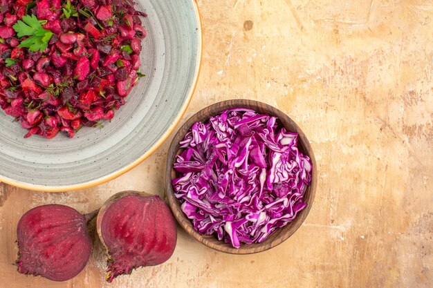 Bovenaanzicht groentesalade met peterseliebladeren met bieten en kom gehakte kool op een houten tafel met vrije ruimte