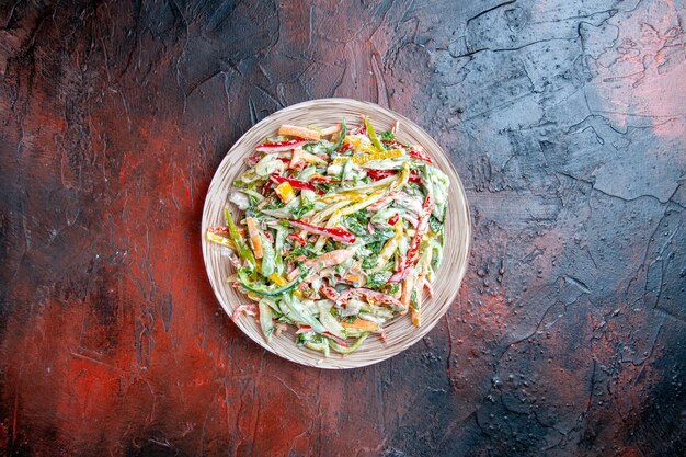 Bovenaanzicht groentesalade op plaat op donkere rode tafel vrije ruimte