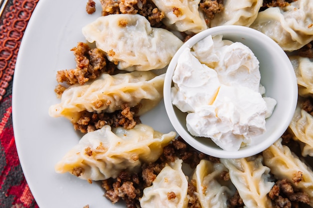 Gratis foto bovenaanzicht gurza lam dumplings met zure room op een plaat