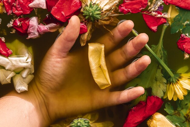 Bovenaanzicht hand met bloemen in zwart water