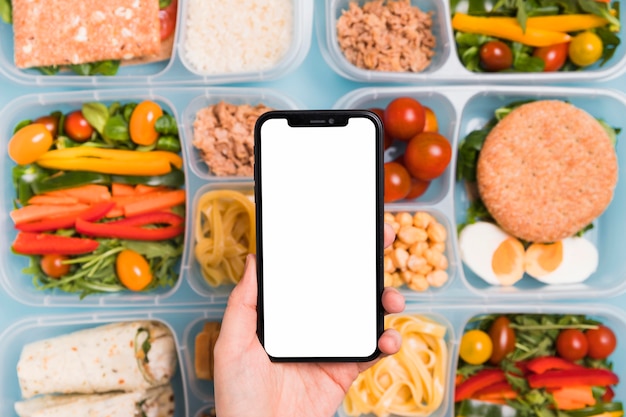 Bovenaanzicht hand met lege telefoon over verschillende lunchboxen