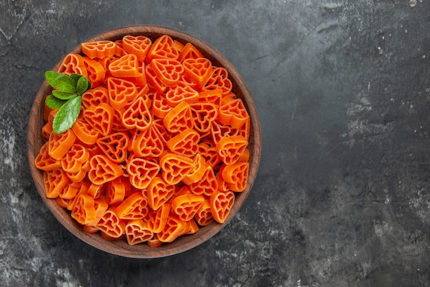 Bovenaanzicht hartvormige rode Italiaanse pasta in een kom op donkere tafel met vrije ruimte