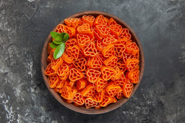 Bovenaanzicht hartvormige rode Italiaanse pasta in een kom op donkere tafel vrije ruimte