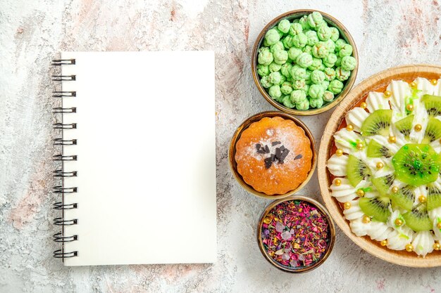 Bovenaanzicht heerlijk dessert met gesneden kiwi's en snoepjes op witte achtergrond dessertcrème fruitcake snoep