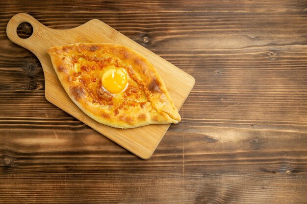 Gratis foto bovenaanzicht heerlijk eierbrood gebakken op bruin houten tafel broodje bak ontbijt eierdeeg