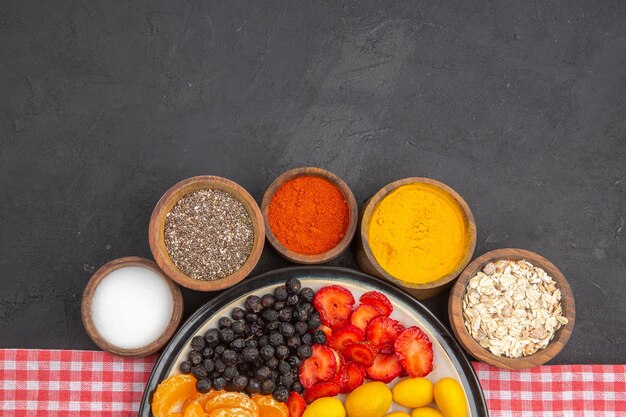 Bovenaanzicht heerlijk gesneden fruit in bord met kruiden op donkere achtergrond