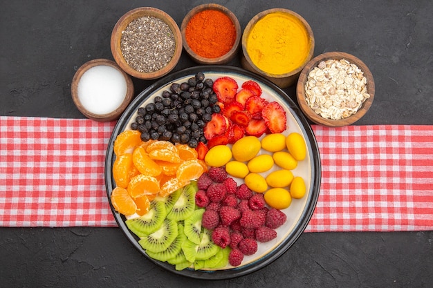 Bovenaanzicht heerlijk gesneden fruit in bord met kruiden op een donkere foto zachte fruitboom exotisch rijp gezond leven