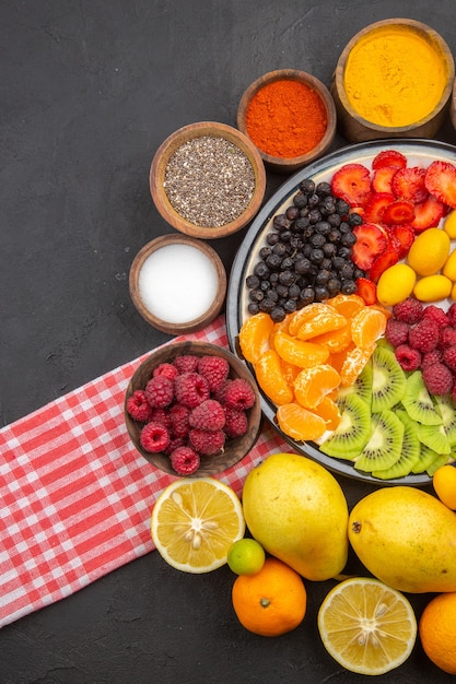 Bovenaanzicht heerlijk gesneden fruit in bord met vers fruit op het donkere fruit exotische foto zachte boom rijp gezond leven