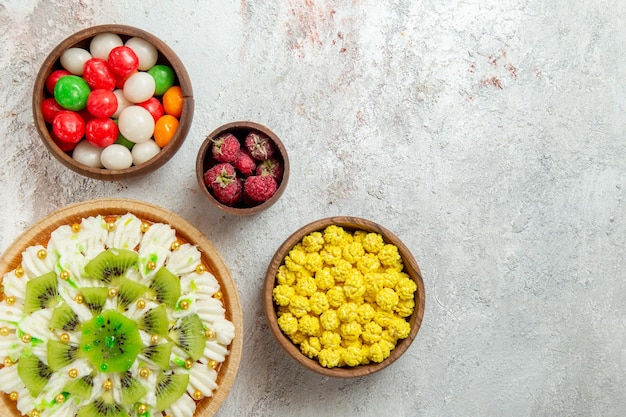 Bovenaanzicht heerlijk kiwi-dessert met snoepjes op witte achtergrond dessert cake crème fruit snoep