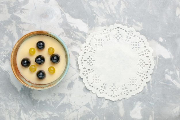 Bovenaanzicht heerlijk romig dessert met fruit bovenop in kleine pot op het licht witte oppervlak fruitroom dessertijs zoet ijs