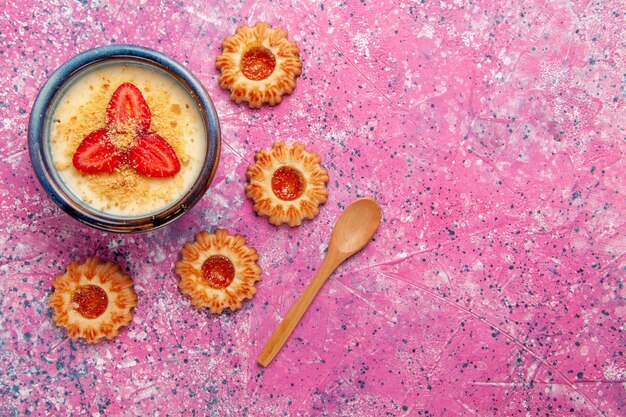 Bovenaanzicht heerlijk romig dessert met rode gesneden aardbeien en koekjes op de roze achtergrond dessertijs kleur zoet ijs