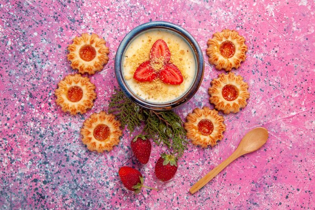 Bovenaanzicht heerlijk romig dessert met rode gesneden aardbeien en koekjes op roze achtergrond dessert-ijs zoet ijs