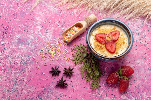 Bovenaanzicht heerlijk romig dessert met rode gesneden aardbeien op lichtroze achtergrond dessert-ijs bessen crème zoet fruit