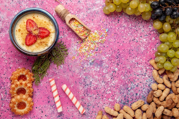 Bovenaanzicht heerlijk romig dessert met verse druiven koekjes en pinda's op lichtroze achtergrond dessert-ijs bessen crème zoet fruit