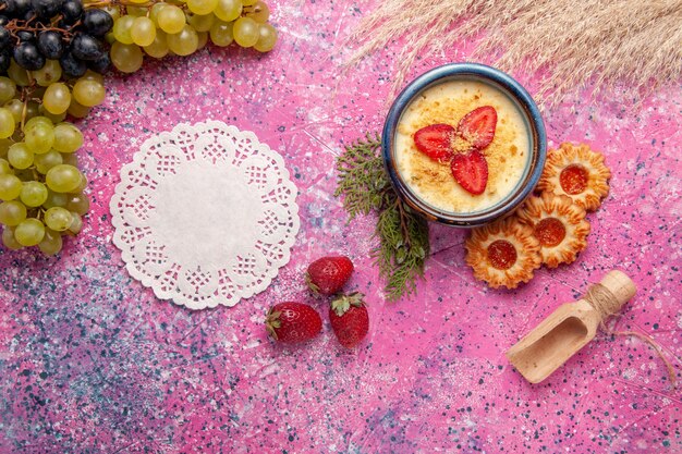 Bovenaanzicht heerlijk romig dessert met verse groene druiven en koekjes op de licht roze achtergrond dessert-ijs bessen crème zoet fruit