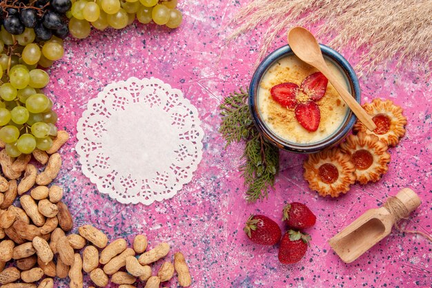 Bovenaanzicht heerlijk romig dessert met verse groene druiven koekjes en pinda's op licht roze achtergrond dessert-ijs bessen crème zoet fruit