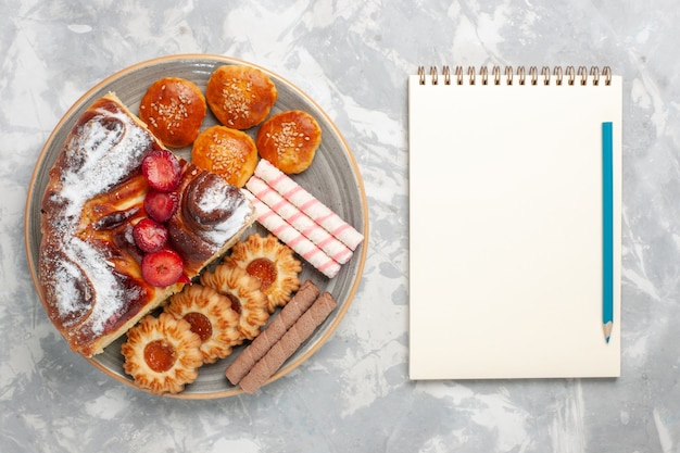 Bovenaanzicht heerlijke aardbeientaart met koekjes en kleine cakes op wit bureau koekje suikertaart zoete taartkoekje