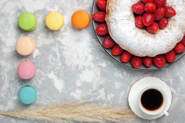 Bovenaanzicht heerlijke aardbeientaart met thee en macarons op wit