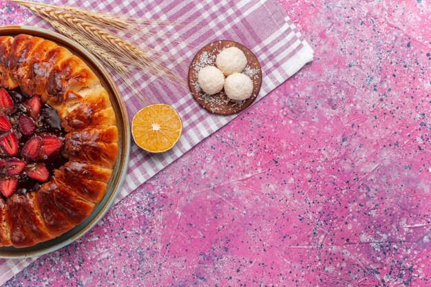 Bovenaanzicht heerlijke aardbeientaart ronde gevormde fruitige cake op een roze