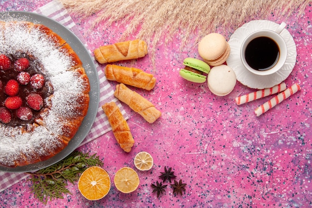 Bovenaanzicht heerlijke aardbeientaart suiker gepoederd met thee macarons op roze achtergrond cake zoete koekje koekjesthee