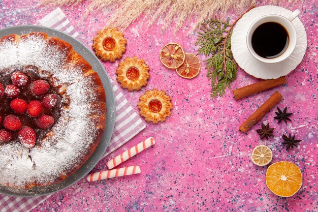 Bovenaanzicht heerlijke aardbeientaart suiker in poedervorm met koekjes en kopje thee op de roze achtergrond cake zoete suiker koekjes koekjes thee