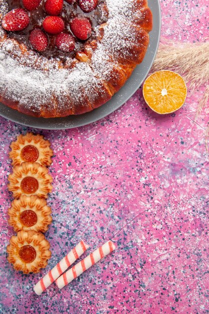 Bovenaanzicht heerlijke aardbeientaart suiker poedertaart met koekjes op roze bureau cake zoete suiker koekjes taart