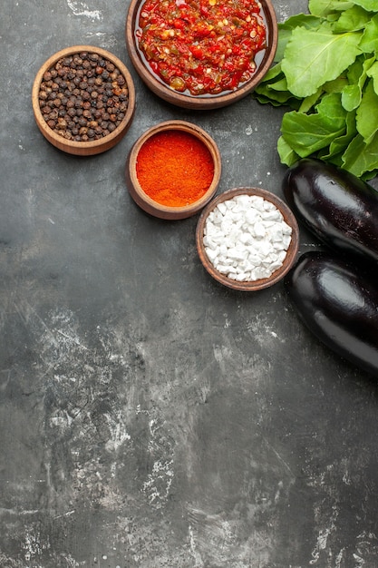 Gratis foto bovenaanzicht heerlijke adjika verschillende kruiden in kleine bawls aubergines greens op grijze achtergrond