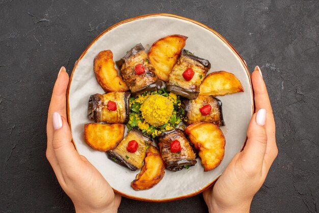 Bovenaanzicht heerlijke aubergine rolt gekookt gerecht met gebakken aardappelen op de donkere achtergrond aardappelschotel maaltijd diner eten koken