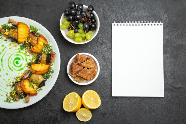 Bovenaanzicht heerlijke auberginebroodjes met gebakken aardappelen in plaat op donkere vloerschotel maaltijd diner eten aardappel groente