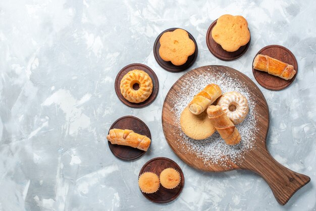 Bovenaanzicht heerlijke bagels met kleine cakes en koekjes op lichte witte achtergrond.