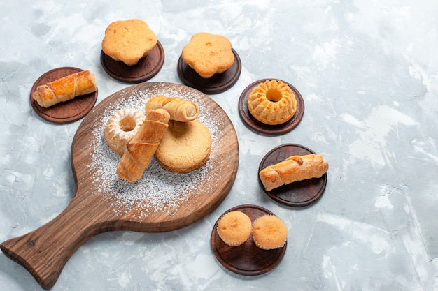 Bovenaanzicht heerlijke bagels met kleine cakes en koekjes op lichte witte achtergrond.