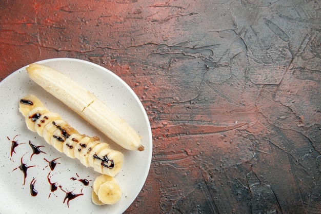 Bovenaanzicht heerlijke banaan met gesneden stukjes binnen plaat op de donkere achtergrond