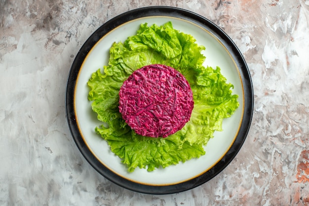 Bovenaanzicht heerlijke bietensalade rond gevormd op groene salade binnen plaat op lichte achtergrond Gratis Foto