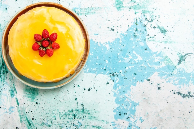 Gratis foto bovenaanzicht heerlijke cake met gele siroop en rode aardbeien op de blauwe cake van het bureaukoekje bak zoete taartsuikerthee