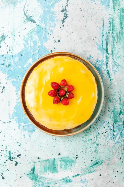 Gratis foto bovenaanzicht heerlijke cake met gele stroop en rode aardbeien op het blauwe oppervlak koekjescake bakken zoete taart suiker thee