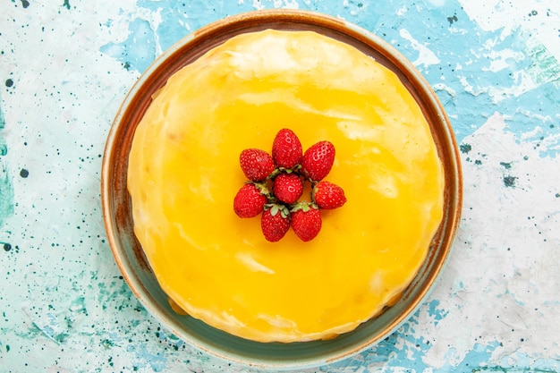 Gratis foto bovenaanzicht heerlijke cake met gele stroop en rode aardbeien op het blauwe oppervlak koekjescake bakken zoete taart suiker thee