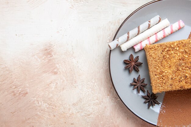 Bovenaanzicht heerlijke cake slice binnen plaat op lichte vloer zoete cake biscuit taart