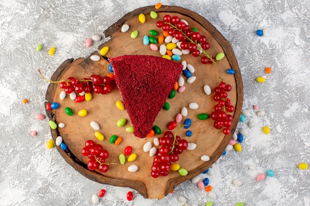 Bovenaanzicht heerlijke cakeplak met room en fruit op het houten bureau met veelkleurige snoepjes cake koekje zoete goodie