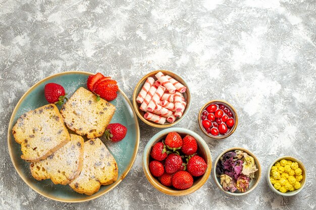 Bovenaanzicht heerlijke cakeplakken met fruit en snoep op lichte ondergrond cake zoete taart