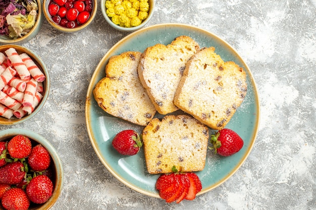 Bovenaanzicht heerlijke cakeplakken met fruit en snoep op lichte ondergrond taarten zoete taart