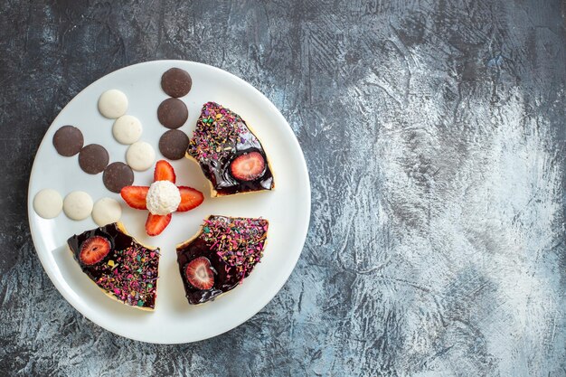 Bovenaanzicht heerlijke cakeplakken met kleine koekjes op donkere ondergrond