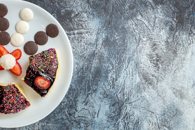 Gratis foto bovenaanzicht heerlijke cakeplakken met kleine koekjes op donkere ondergrond