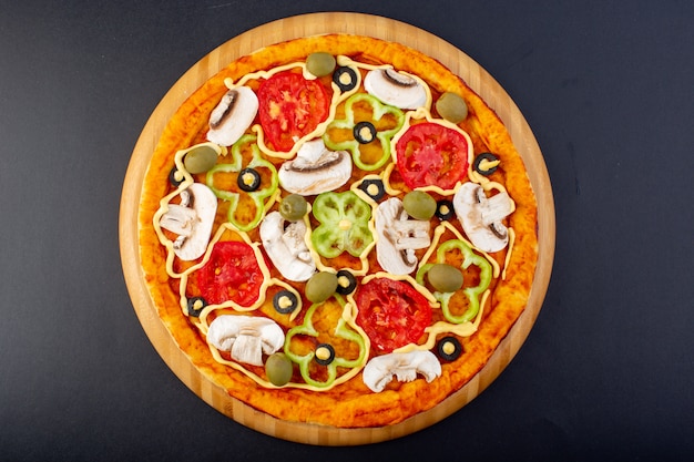 Bovenaanzicht heerlijke champignonpizza met rode tomaten paprika olijven en champignons allemaal binnen gesneden op het donkere bureau eten maaltijd pizza italiaans