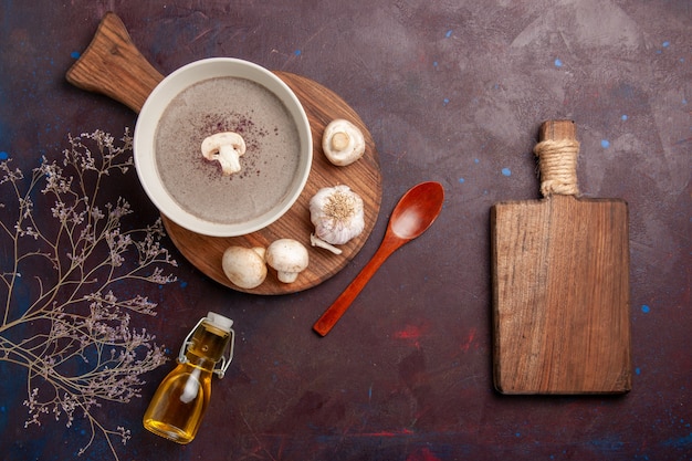 Bovenaanzicht heerlijke champignonsoep met verse champignons en olie op donker bureau