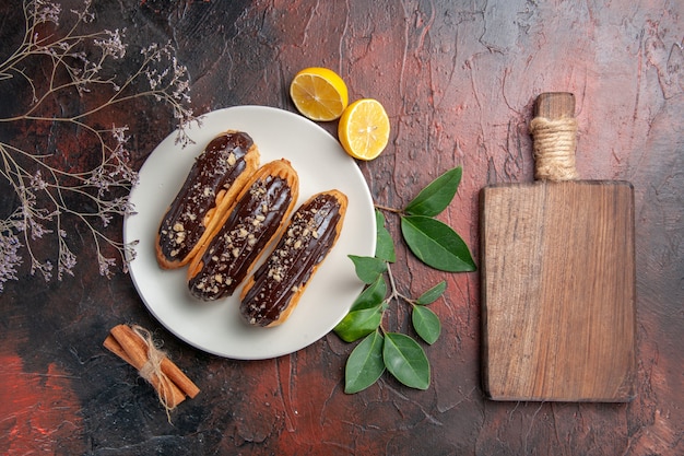 Bovenaanzicht heerlijke choco eclairs binnen plaat op donkere tafel taart taart zoet dessert