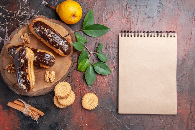 Bovenaanzicht heerlijke choco eclairs met koekjes op donkere tafel dessert cake zoet